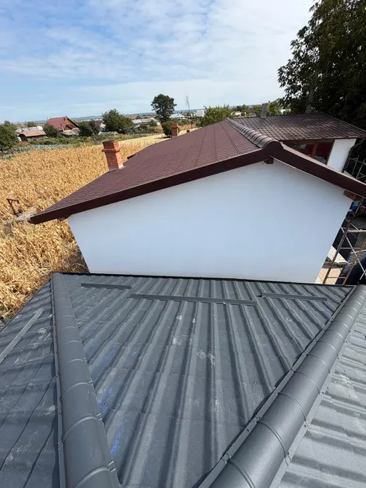Fronton cu schelă de montaj, acoperiș din țiglă maro-vișinie, horn de cărămidă