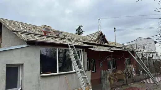 Acoperiș în lucru, membrană bituminoasă și șipci de lemn vizibile, doi muncitori, cer înnorat