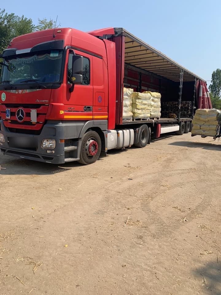 Camion încărcat cu paleți de saci galbeni, în curtea fabricii