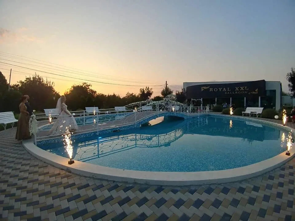 Piscina la apus, cu fântâni luminoase și cer portocaliu